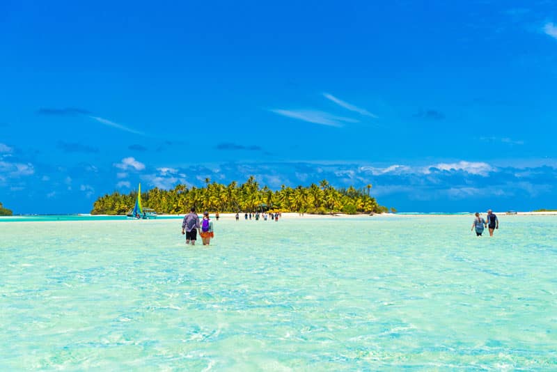 People walking true turquoise sandbank, Aitutaki island, Cook Is