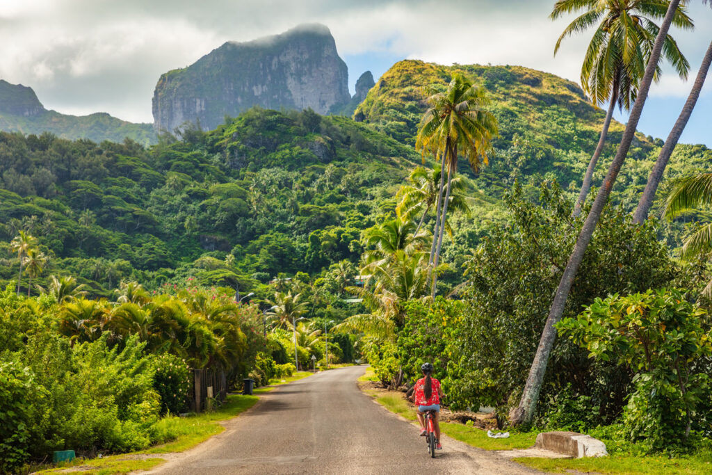 Island Escapes Bora Bora Tahiti Holidays Biking tourist on summer vacation travel discovering by e bike cycling through forest of Bora Bora island in Tahiti French Polynesia