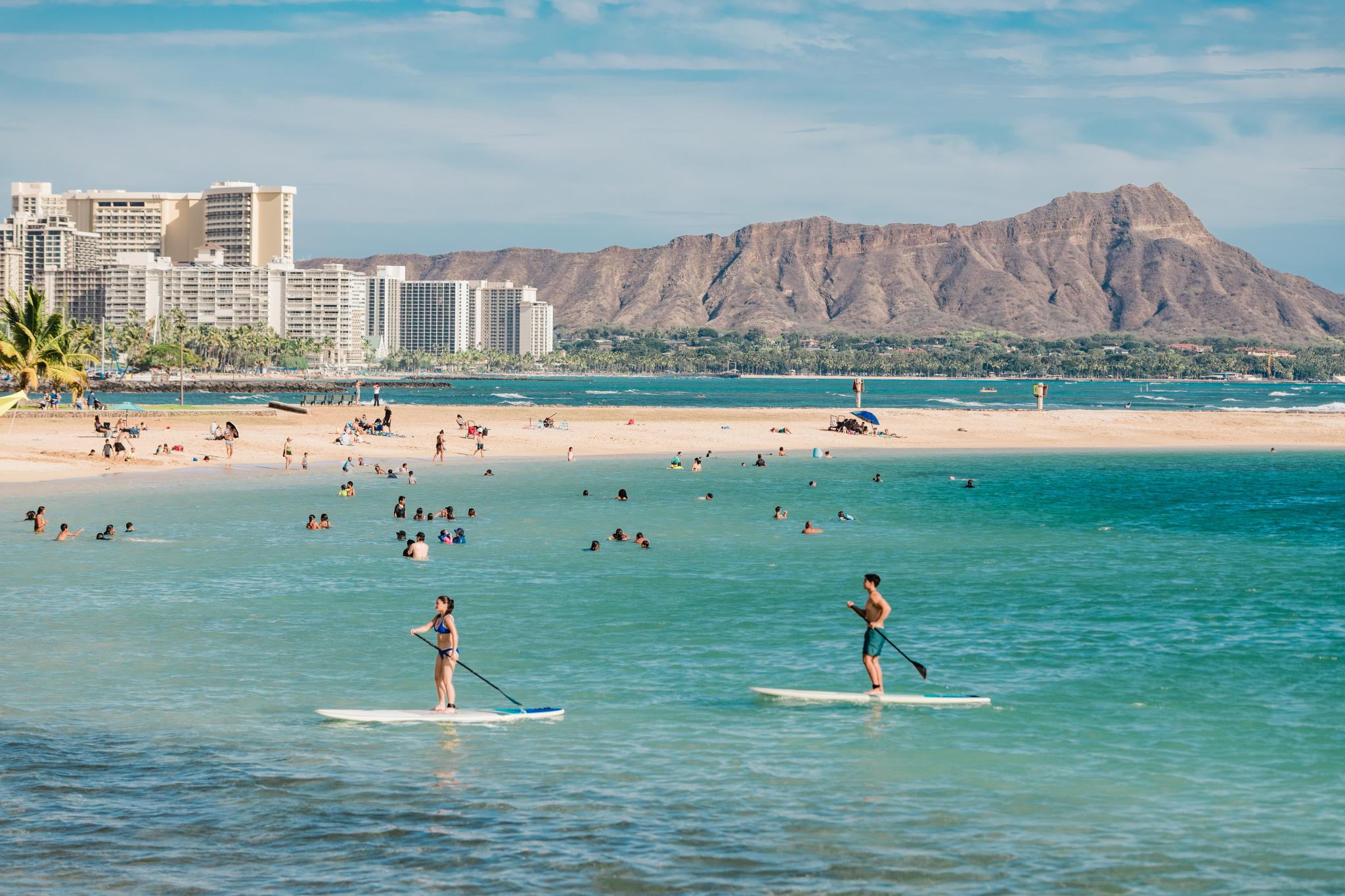 People stand up paddleboard in the Magic Island Lagoon Oahu